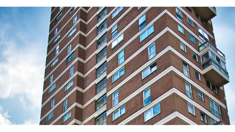 A redbrick tower block against a blue cloudy sky